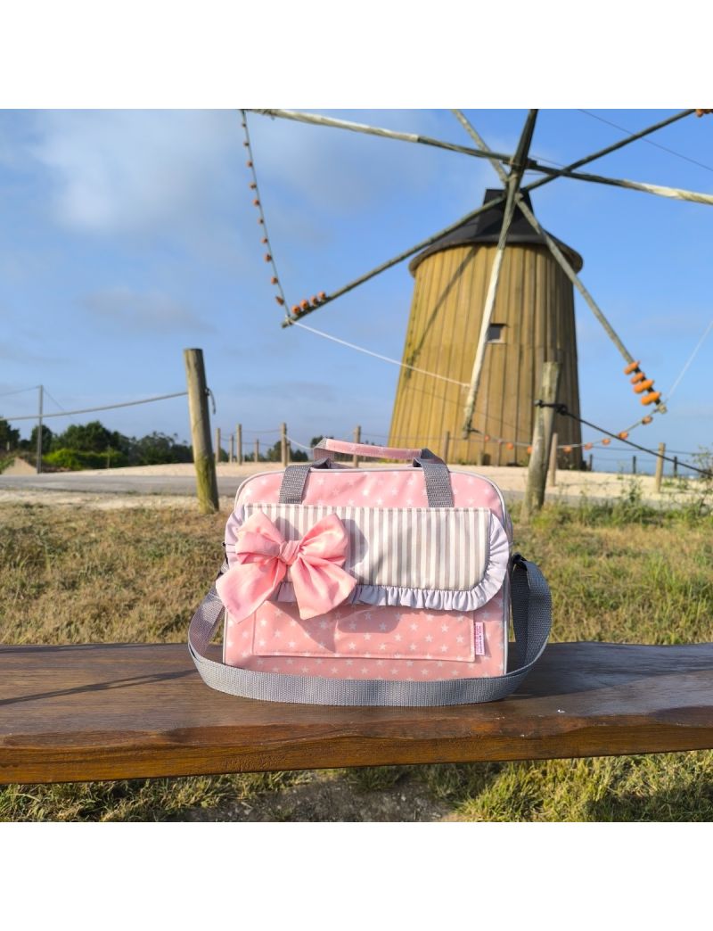 Lancheira térmica em tecido plastificado rosa com estrelas brancas. Com bolso frontal e pala com folho cinza e laço rosa. Ideal para o trabalho ou escola