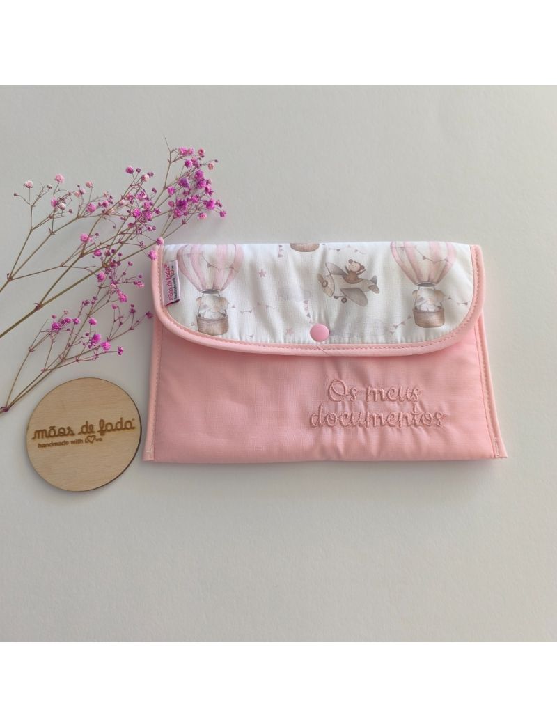 Porta documentos em formato envelope cor de rosa com pala com padrão de balões de ar e aviões em tons suaves 
