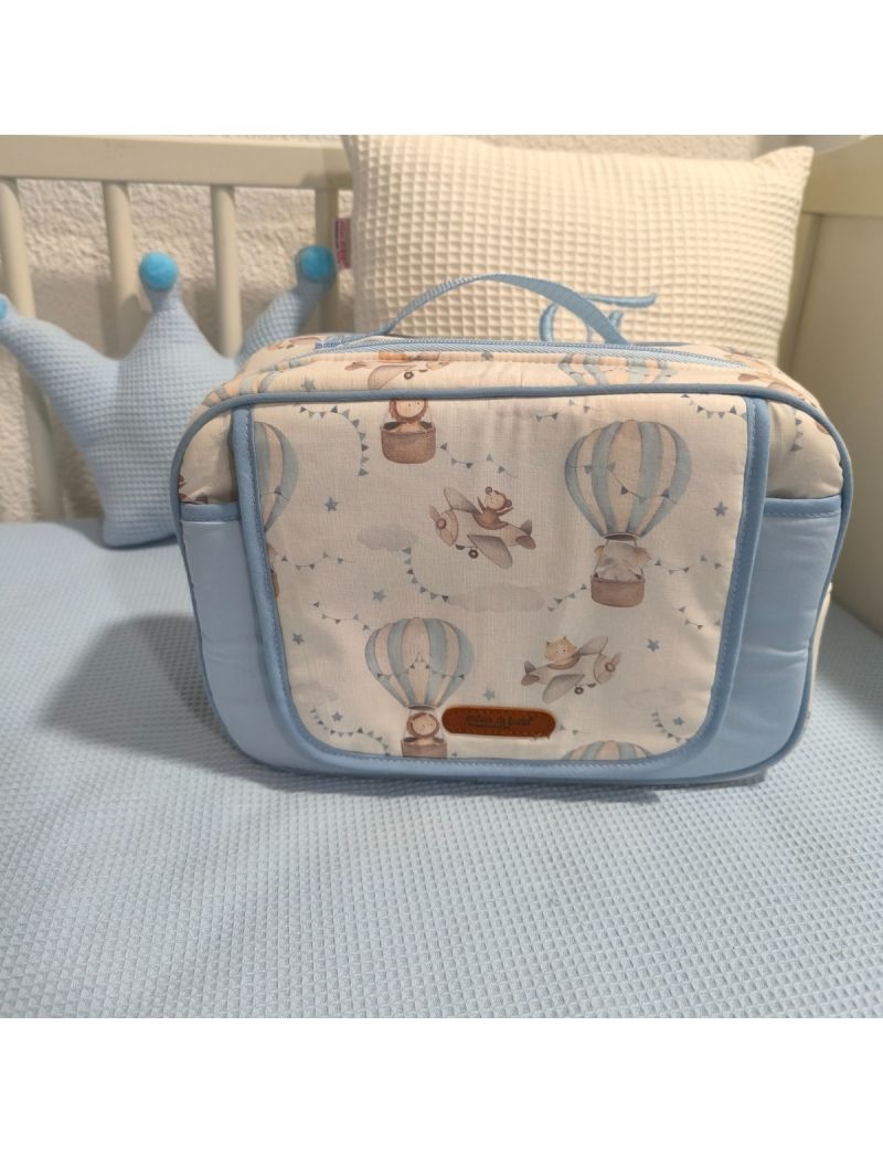 Bolsa fechada, com pala com padrão de balões de ar quente em tons de azul e bege. Com alça e fecho em azul claro 