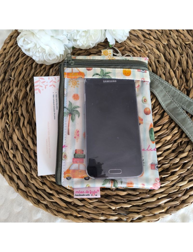 Parte da frente da Bolsa 3 em 1 com desenhos de sol, palmeiras e carrinhos. Bolsa transparente com um telem&oacute;vel. Fita amov&iacute;vel para colocar ao pesco&ccedil;o. Bolsa lateral com documentos colocados. 