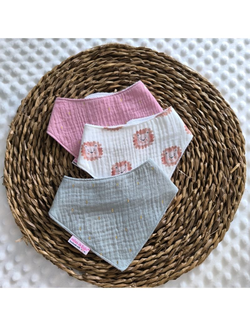 Conjunto de tr&ecirc;s babetes badana em musselina dispostos sobre uma base de verga circular. O pack apresenta um babete com le&otilde;es, ladeado por dois babetes em tons de rosa e em tons de verde com pequenos detalhes dourados