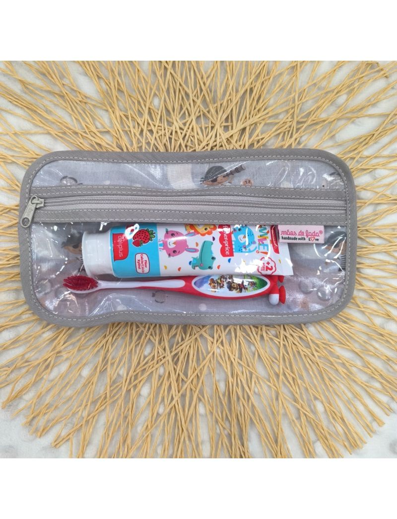 Bolsa de higiene para crian&ccedil;a em tons de cinzento com padr&atilde;o de piratas. Fecho cinza claro. No interior possui uma escova e pasta de dentes como exemplo