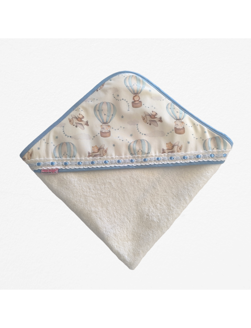Toalha de banho em turco branco com capuz com padrão de balões de ar quente e aviões em tons suaves. Com bordado inglês com fita azul